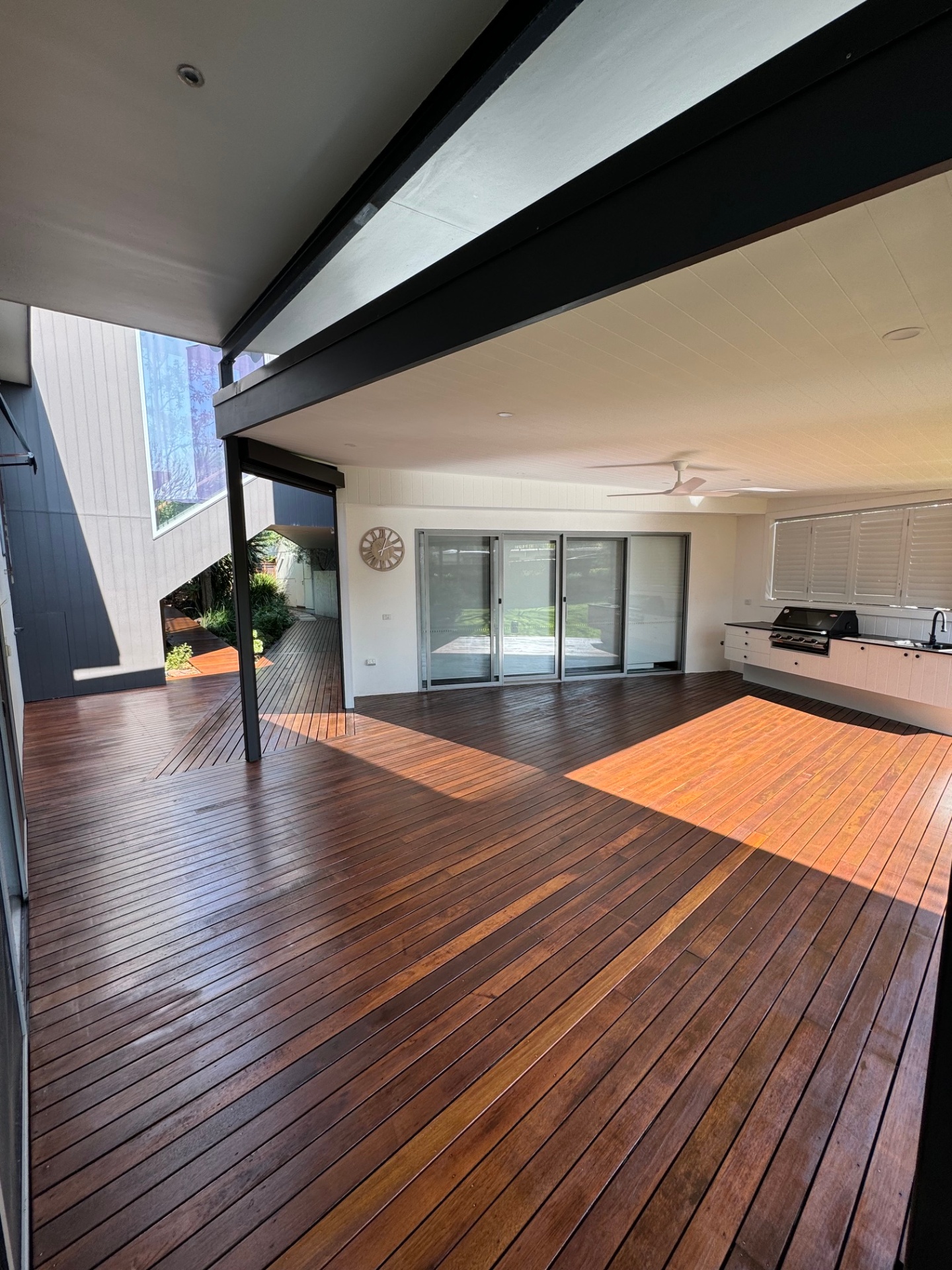 Expansive spotted gum deck flowing under a raked ceiling to a built-in outdoor kitchen and BBQ.